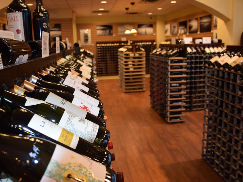 Angled close-up of fully stocked free-standing wine racks with modular storage in the background at Vintology