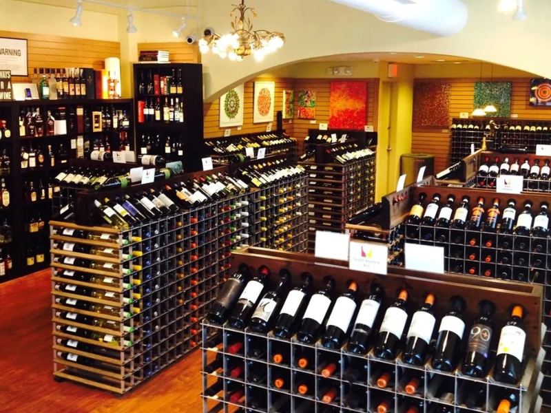 Free-standing modular wine racks arranged in aisles beneath colorful wall art at Vintology's current Scarsdale location
