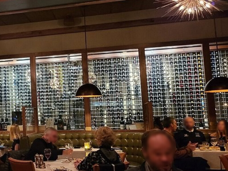 Full-height aluminum-framed wine rack system with polished surfaces reflecting ambient light at a steakhouse in Indianapolis, Indiana