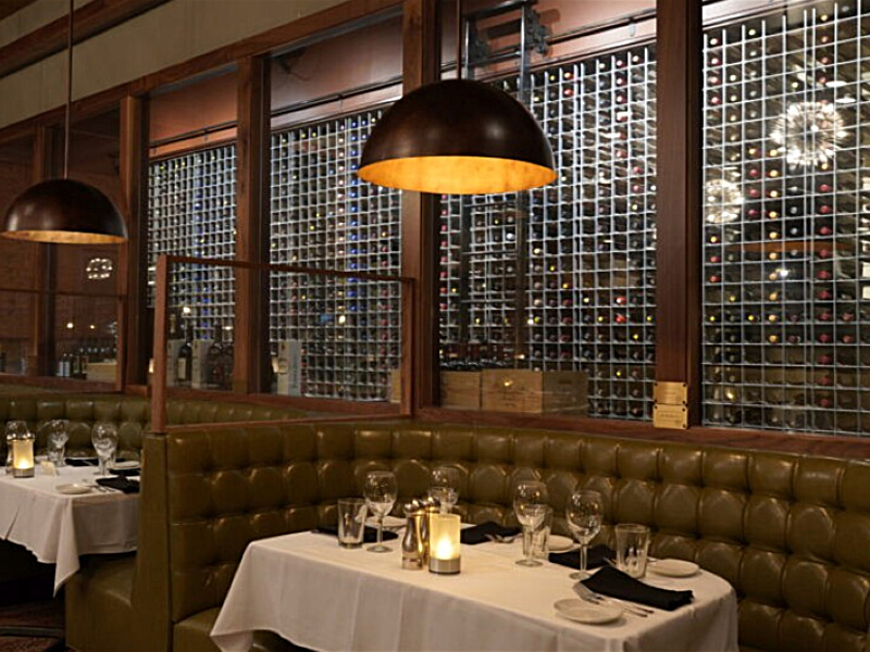 Two-story dining room with floor-to-ceiling wine wall as the architectural focal point at a steakhouse restaurant location