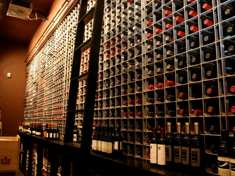Close-up of aluminum-framed wine rack display with dome pendant lighting and precise bottle positioning at a steakhouse in Omaha, Nebraska